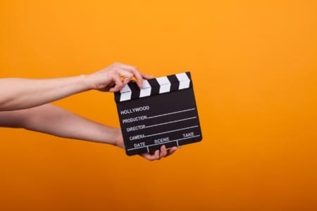 Photo of movie production clapper board isolated in studio over yellow background. Film accessory isolated.
